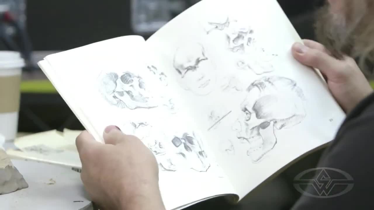 Norman Cabrera flips through Atlas of Human Anatomy for the Artist to show the useful information found inside.