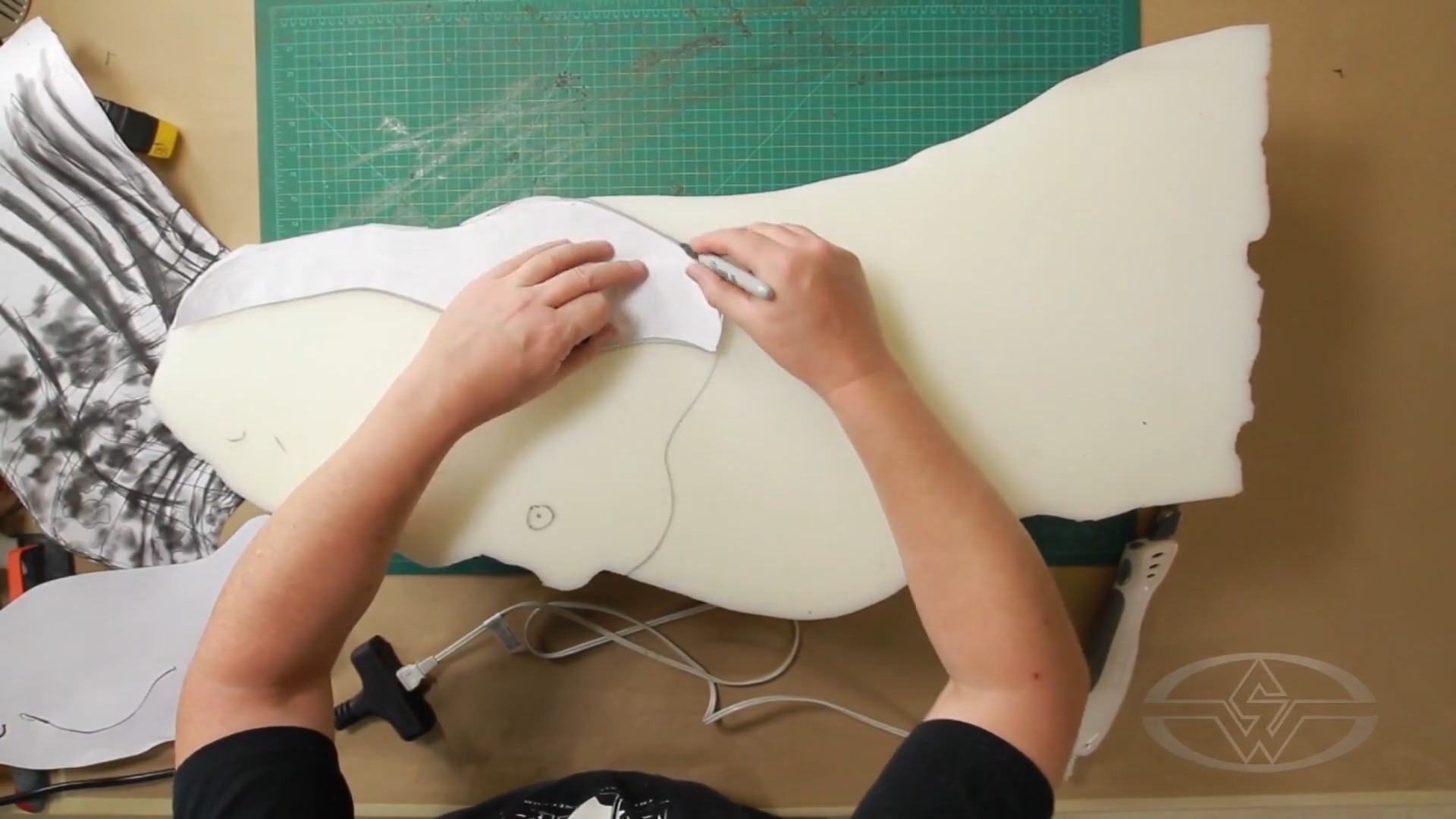 To keep the sculpture balanced, Ted Haines flips the piece of foam over again tracing the outlines of the jaw, mouth, bridge of nose, and eye before carving into it.