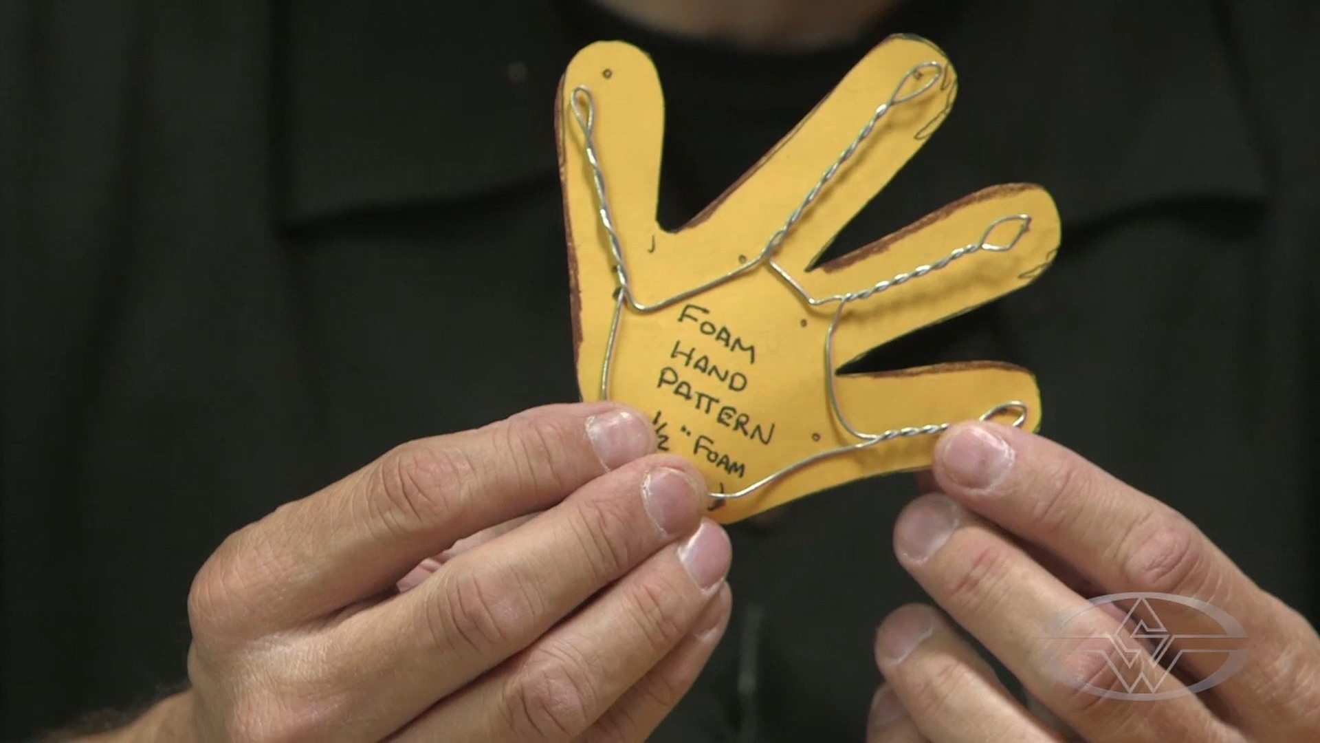 BJ Guyer holds his hand armature&nbsp;with completely twisted fingers and open-looped fingertips up against his hand pattern.