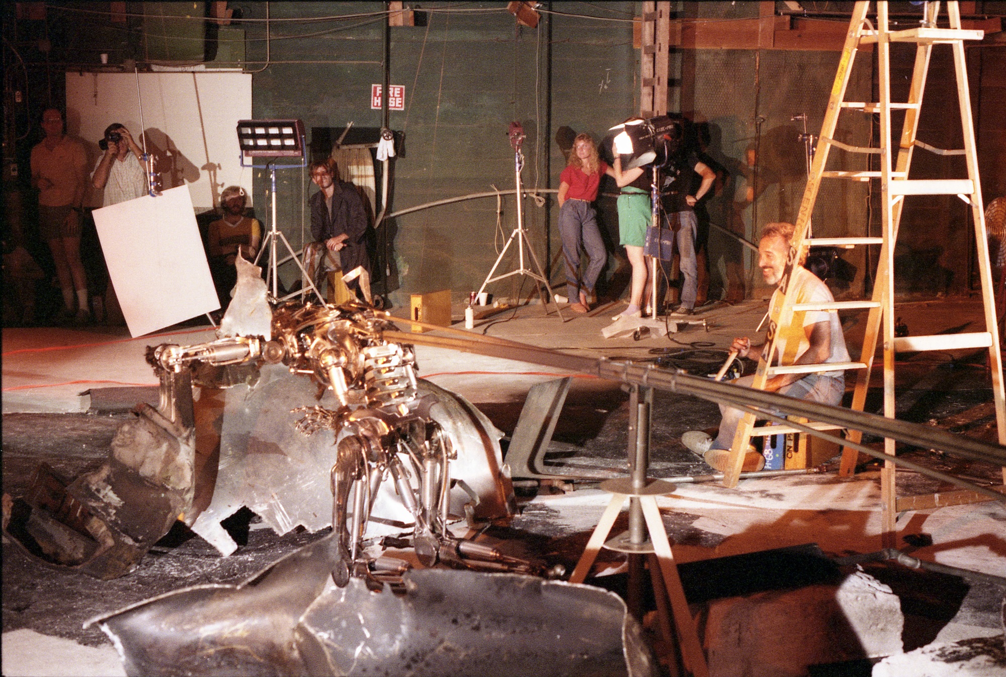 Jim Cameron (seated, center) and Michael Biehn (right) watch as Stan Winston and his crew prepare to rehearse a shot of the endoskeleton rising from the soon-to-be flaming debris of the exploded tanker truck. Image courtesy of Hemdale Film, Pacific Western Productions, Euro Film Funding, and Cinema '84.